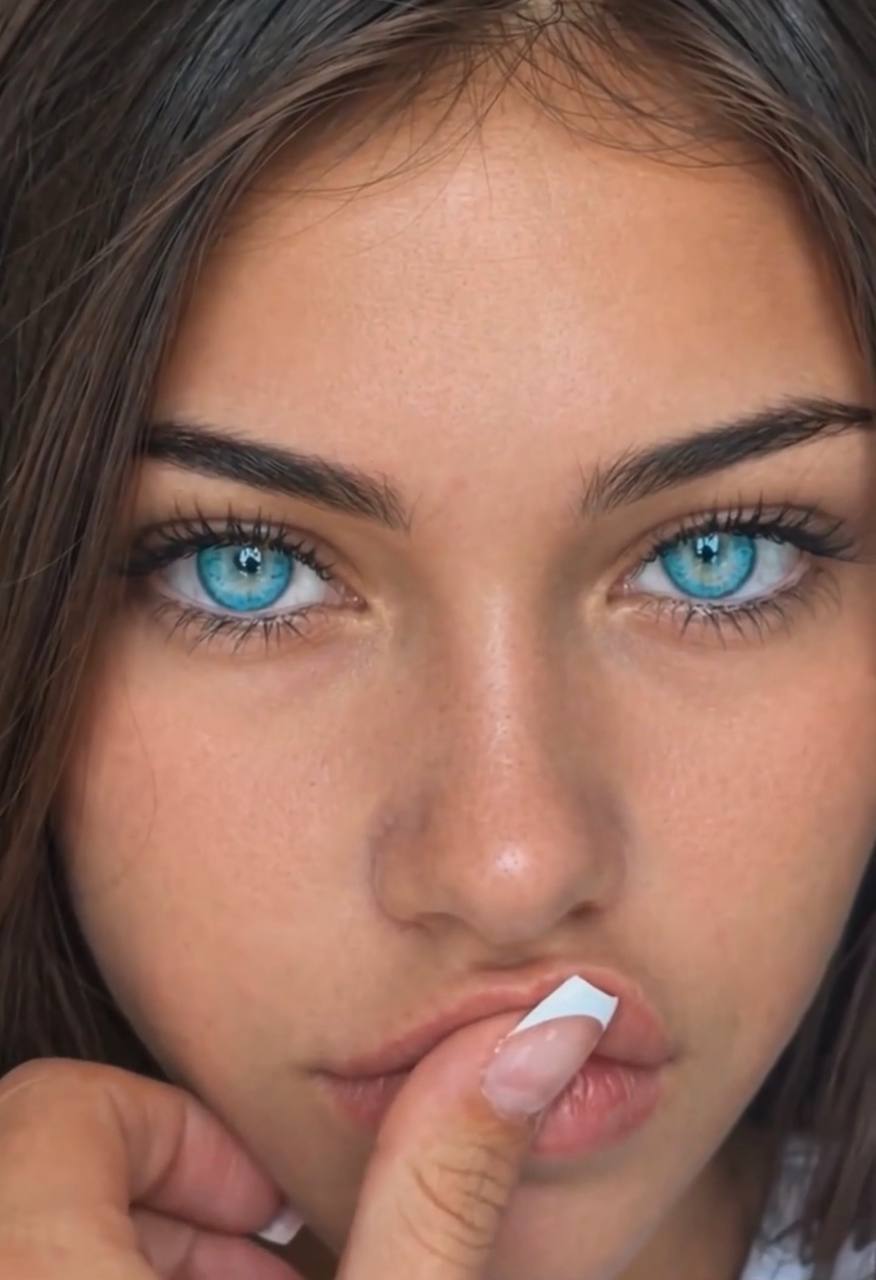 Close-up of Drekkah with turquoise-blue eyes, dark hair and white French-tip nails